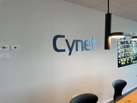 Cynet: שלט לוגו למשרד על קיר לבן.
